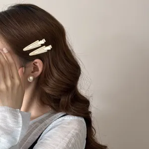 Gros plan de barrettes à cheveux triangulaires crème élégantes portées par un mannequin