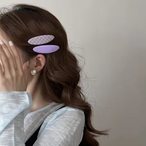 Vue latérale d'élégantes barrettes à cheveux en tissu violet sur cheveux bruns ondulés
