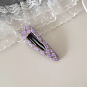 Gros plan détaillé d'une pince à cheveux en tissu à carreaux violets sur de la dentelle