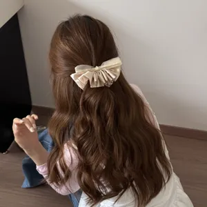 Close-up detail of an elegant cream French style bow hair clip worn on long wavy brown hair