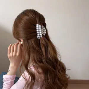 Vista posterior de una mujer con cabello castaño largo usando una pinza de cuadros.