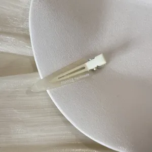Gros plan d'une pince à cheveux triangulaire crème posée sur une assiette blanche.