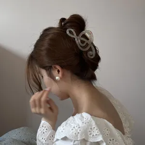 Primer plano de una elegante pinza para el cabello con forma de clave de sol en tono nacarado