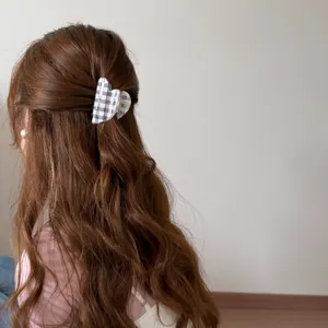 Primer plano de pinza de corazón a cuadros sujetando un semirecogido en pelo castaño.