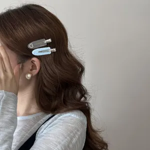 Detailed side view of two pastel acrylic duckbill hair clips on brown wavy hair
