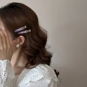 Détail de deux élégantes barrettes en acétate violet sur des cheveux bruns ondulés