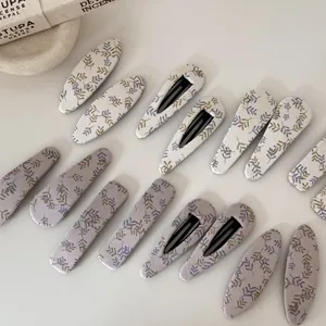 Vue détaillée de barrettes à cheveux en tissu fleuri en beige et violet