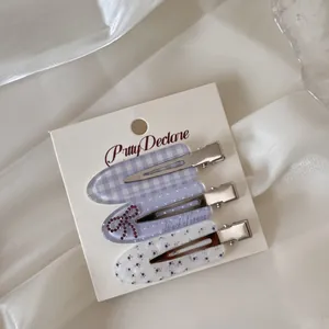 Detail view of three Korean style acrylic hair clips with floral and gingham patterns.