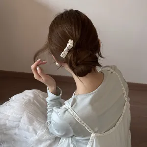 Detail view of a black and white polka dot bow hair clip in an elegant low bun.