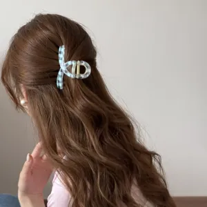 Detalle de una pinza para el pelo a cuadros azules de estilo coreano en pelo castaño.