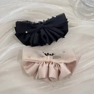 Detail of ruffled fabric banana hair clips with rhinestones in black and champagne.