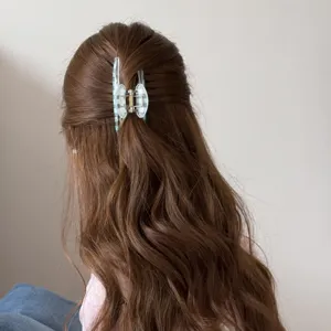 Detalle de pinza de pelo coreana de cuadros azules transparentes en pelo ondulado.