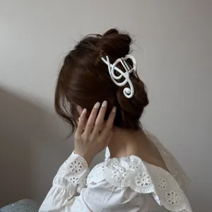Elegante pinza para el cabello con nota musical blanca en un peinado de moño de mujer.