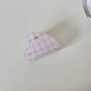 Detalle de pinza para el pelo con forma de corazón a cuadros rosas y acabado brillante.
