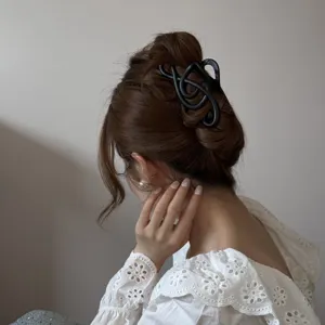 Elegante pinza para el cabello negra con forma de clave de sol en el moño de una modelo chic.