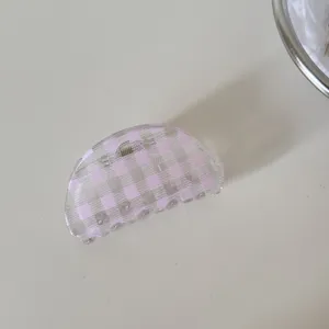 Primer plano de una pinza para el pelo a cuadros rosa transparente sobre fondo claro.