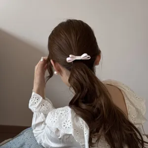 Close-up view of a pink double-layered ribbon bow hair tie used on an elegant ponytail.