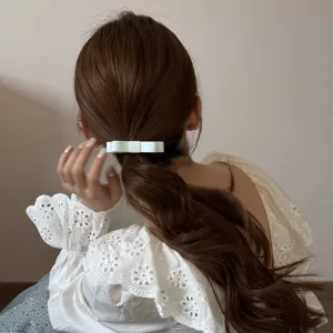 Back view of a woman with a white fabric double-layer bow hair tie in a ponytail