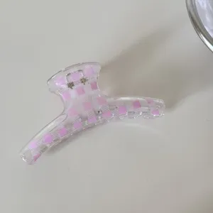 Detalle de una pinza para el cabello de cuadros rosa transparente con acabado brillante.