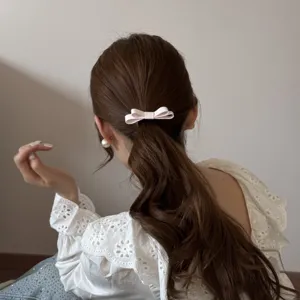 Detailed view of a sweet pink double-layered fabric bow hair tie on a low ponytail