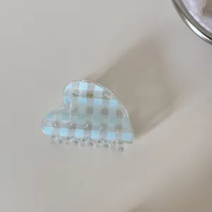 Detalle de una pinza para el cabello translúcida en forma de corazón con cuadros