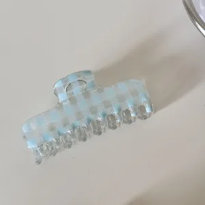 Detalle de una pinza para el pelo transparente con un patrón de cuadros azul claro