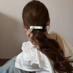Detailed macro shot of a light blue double-layered fabric bow hair tie on a low ponytail