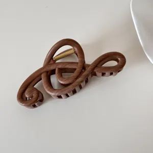Detalle de una pinza para el pelo marrón con forma de clave de sol y textura de madera