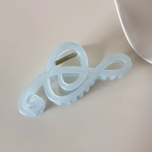 Detalle de una pinza para el cabello en forma de nota musical hecha de resina azul suave.