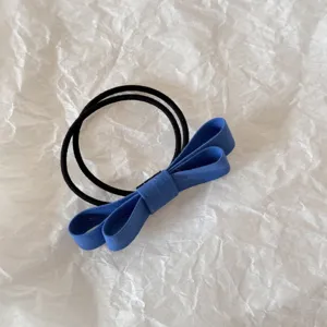 Close-up of blue double-layered fabric bow hair tie on textured white background