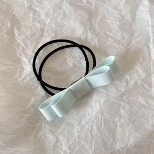 Close-up detail of a light blue fabric bow hair tie on a white crinkled background