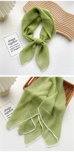 Detailed view of a light green sheer thin silk scarf necktie with white borders