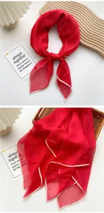 Macro detail of lightweight red silk scarf featuring elegant cream edge contrast piping