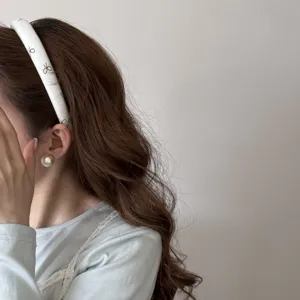 Gros plan d'un serre-tête blanc de style français avec des motifs de nœuds noirs