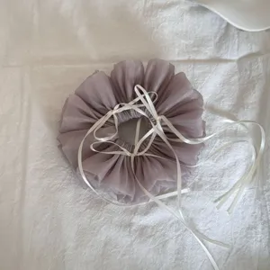 Detaillierte Ansicht eines staubig-violetten Mesh-Haargummis mit weißen Seidenbändern.