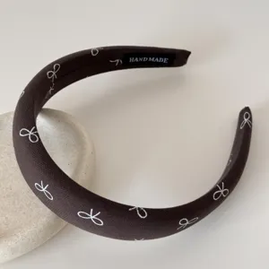 Détail d'un serre-tête marron foncé style français avec nœuds brodés