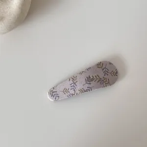 Détail d'une pince à cheveux BB en tissu fleuri avec d'élégants motifs de feuilles violettes