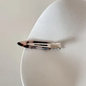 Détail de la barrette en acétate écaille avec gravure FRANCE Handmade sur assiette blanche.