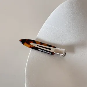 Gros plan d'une barrette étroite en acétate écaille avec inscription FRANCE Handmade.