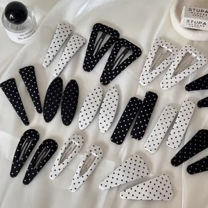 Vue détaillée de diverses pinces à cheveux à pois noirs et blancs sur du tissu en soie