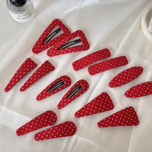 Vue détaillée de barrettes à pois rouges de formes variées sur fond de soie blanche