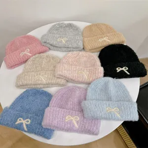 Detailed overhead view of multiple colorful fuzzy knitted beanies with bow decorations