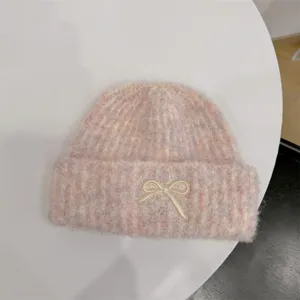 Close-up of a pink multi-colored knit beanie with a cute cream bow applique