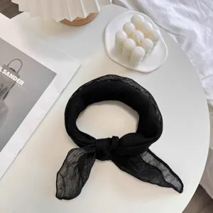 Detailed texture of a black 100% pure linen scarf knotted on a minimalist table