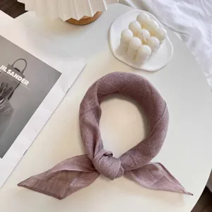 Close-up of textured dusty rose linen scarf tied in a stylish knot on a white table.