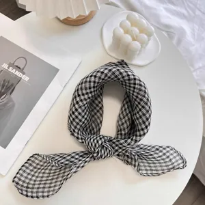 Close-up of a black and white checkered linen scarf tied in a knot on a white table.