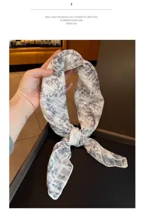 Detail of a floral print cotton linen square scarf held by hand, showing texture.