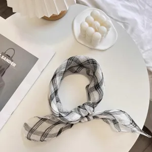 Detailed view of a black and white plaid linen scarf tied elegantly on a minimalist table