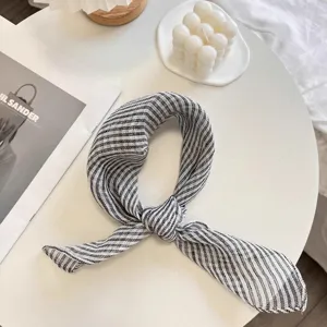 Detailed view of a knotted black and white striped 100% pure linen scarf on a table