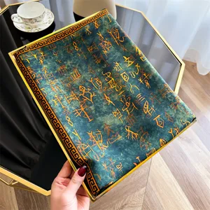 Detailweergave van groenblauwe vintage zijden sjaal met goudkleurige oude schriftpatronen